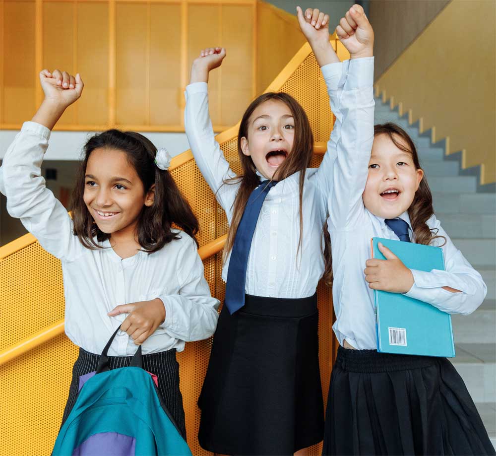 3 girls in school uniforms jumping of joy